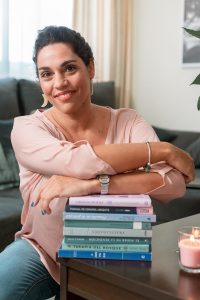 Mujer apoyada en una montaña de libros y mirando al techo sonriente